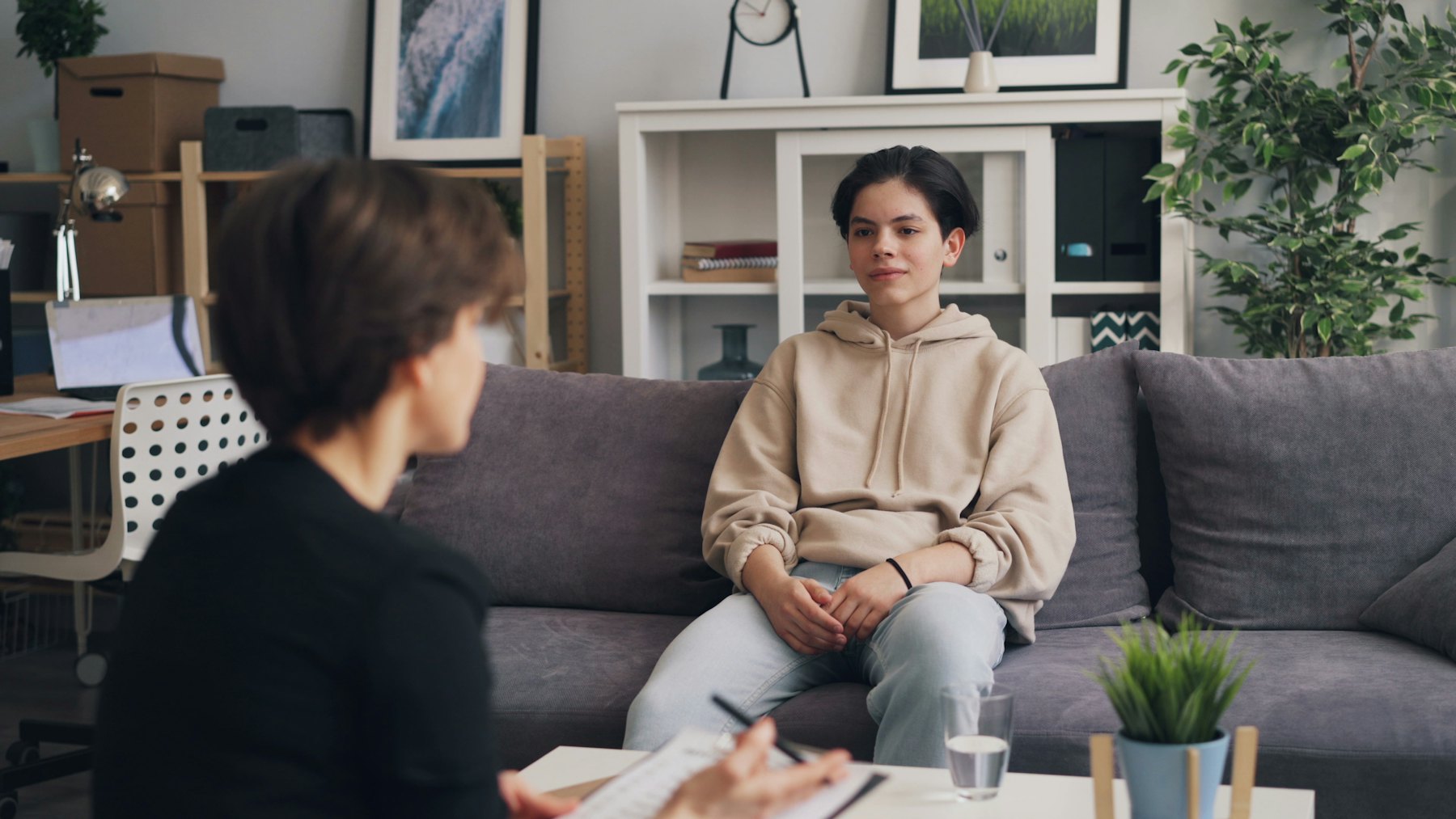 Two women sitting on a couch, one listening to the other