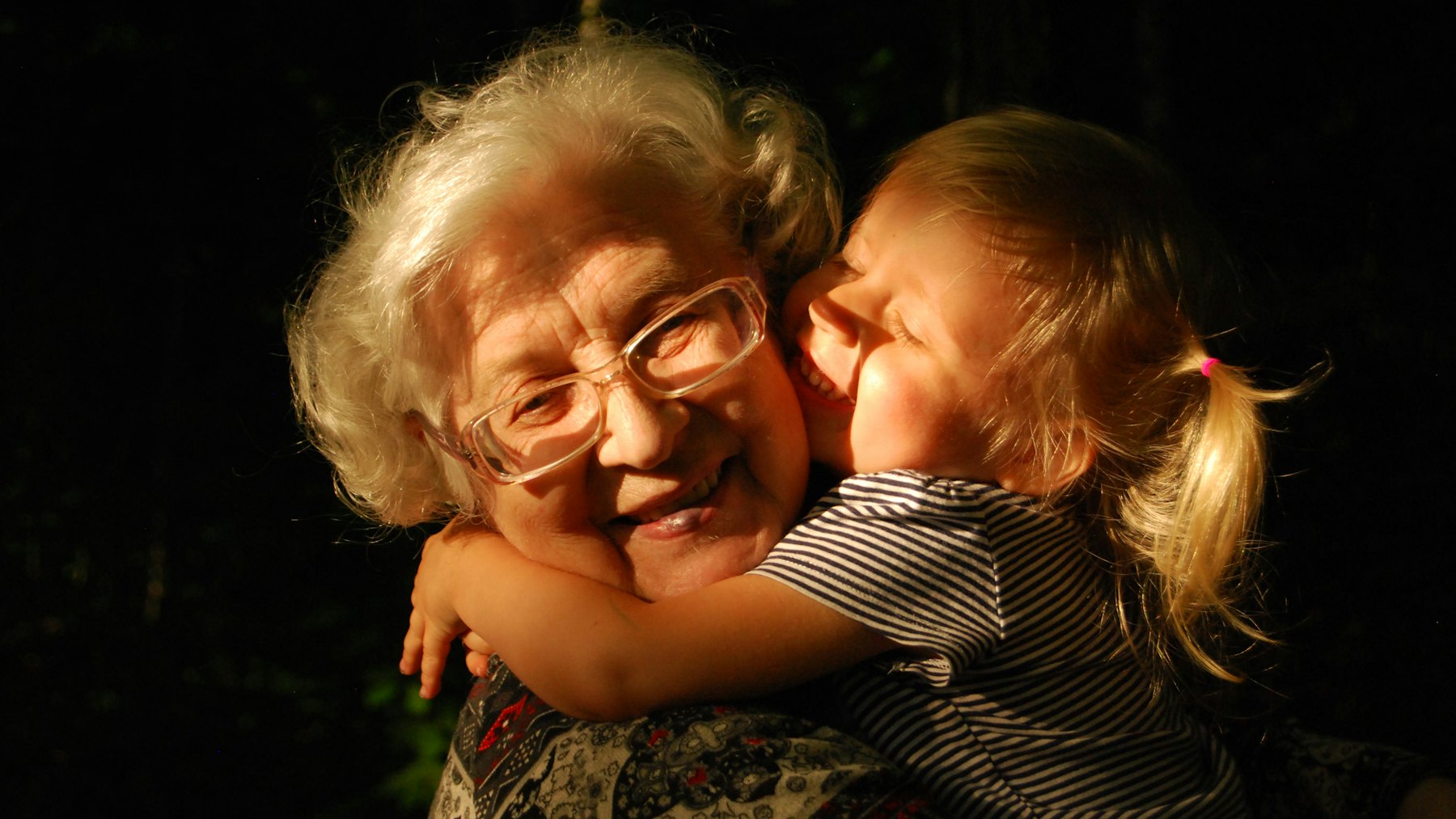 An older woman holding a small girl cheek to cheek