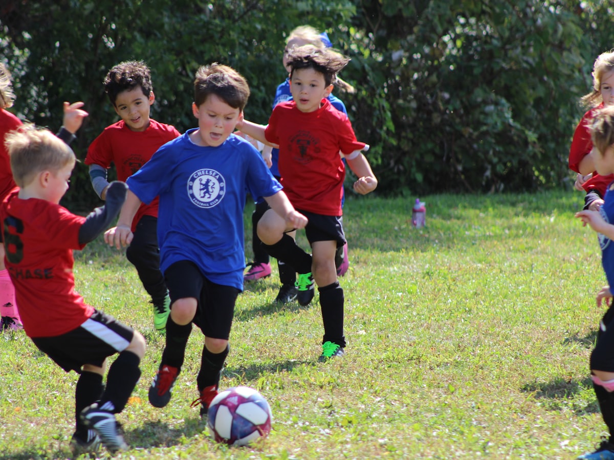 A boy in a soccer kit kicking a ball on a grass field — Health